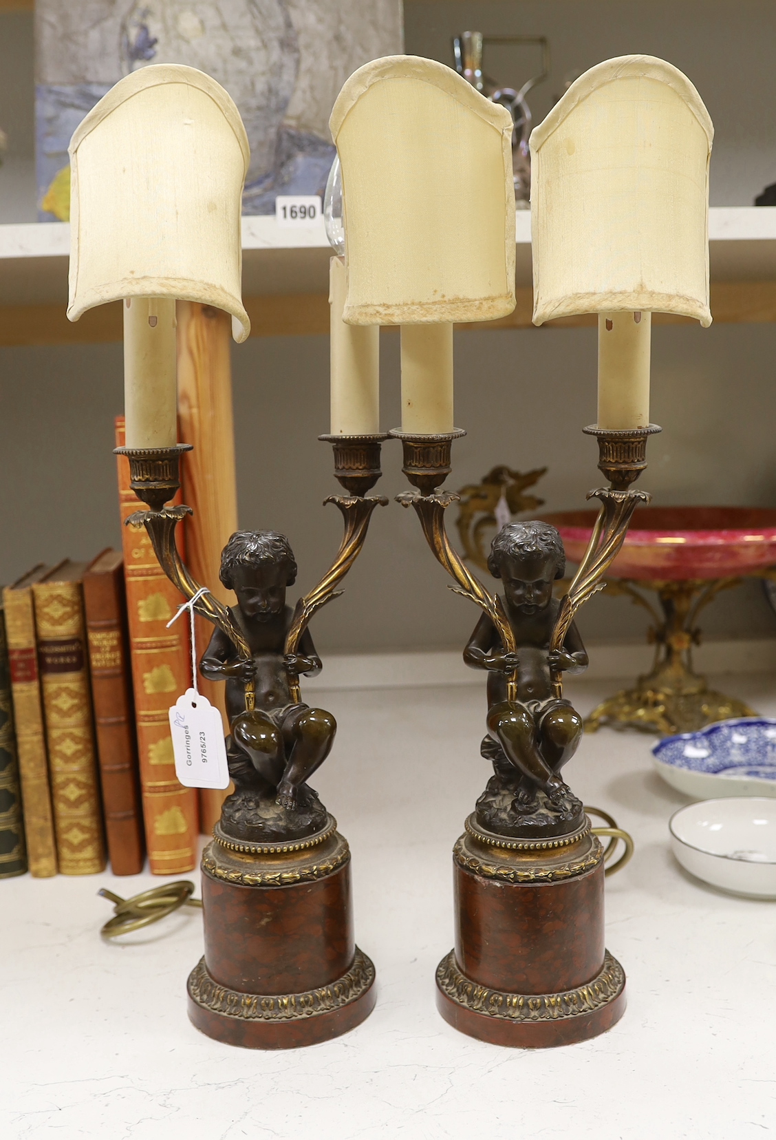 A pair of late 19th century French bronze and ormolu cherub two branch candelabra, converted to lamps, 49cm high including light fitting and bulb